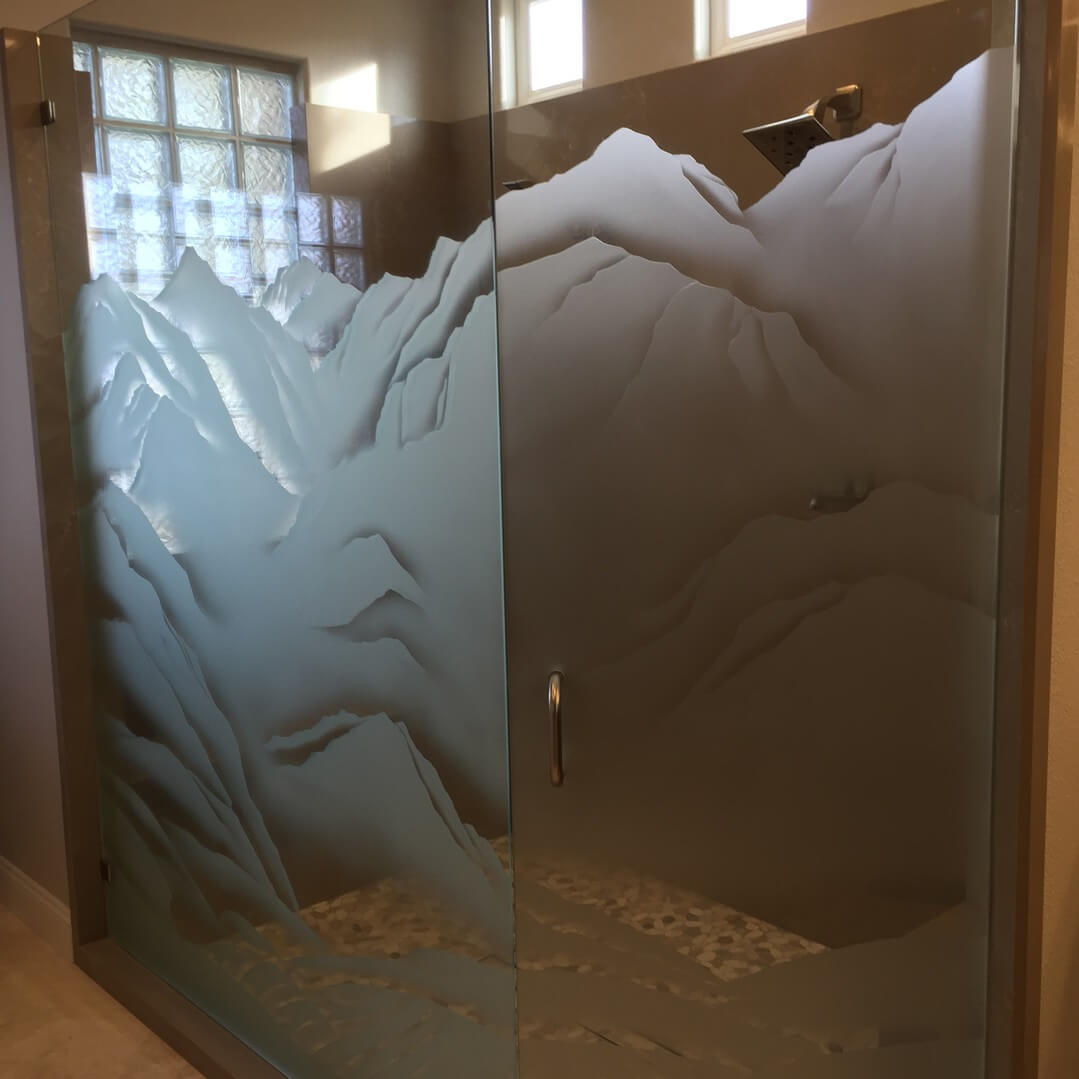 A shower with a glass door and a mountain scene on the side.