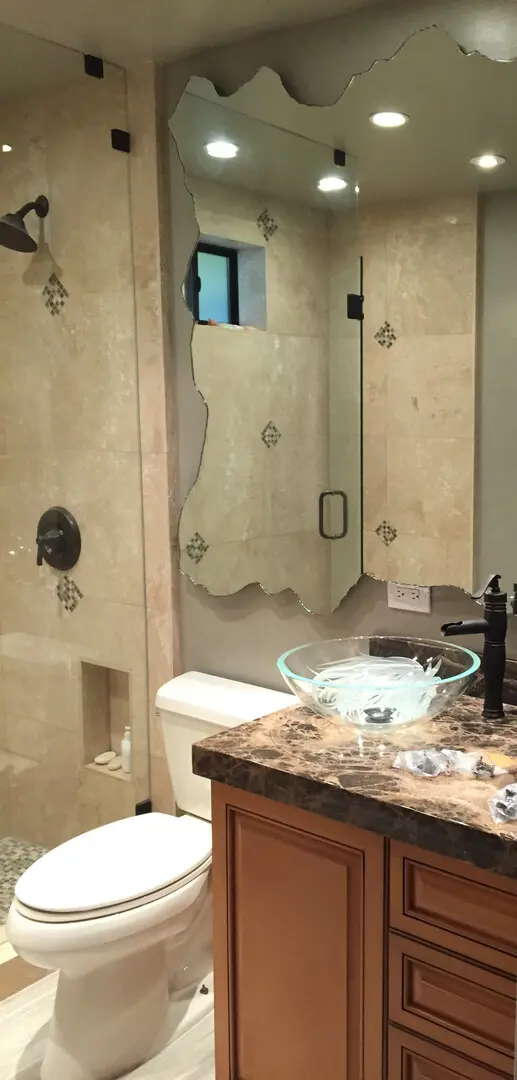 A bathroom with marble counter tops and a glass bowl sink.
