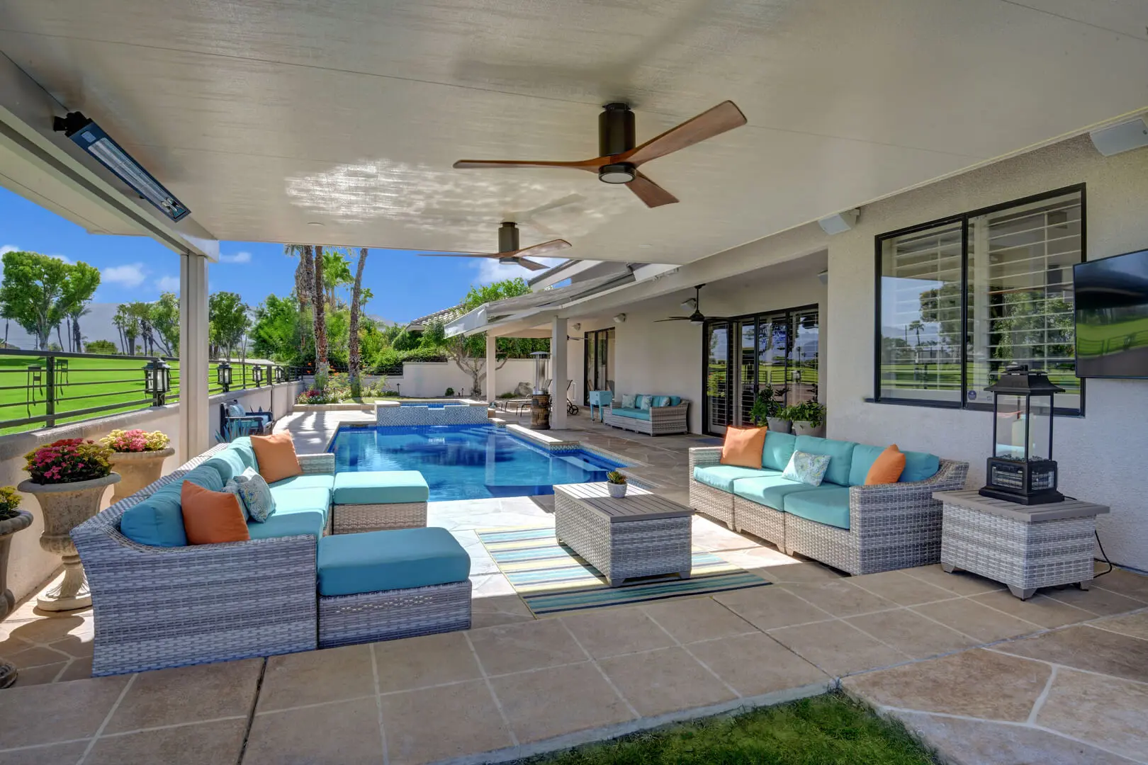 A patio with couches and pillows in front of the pool.