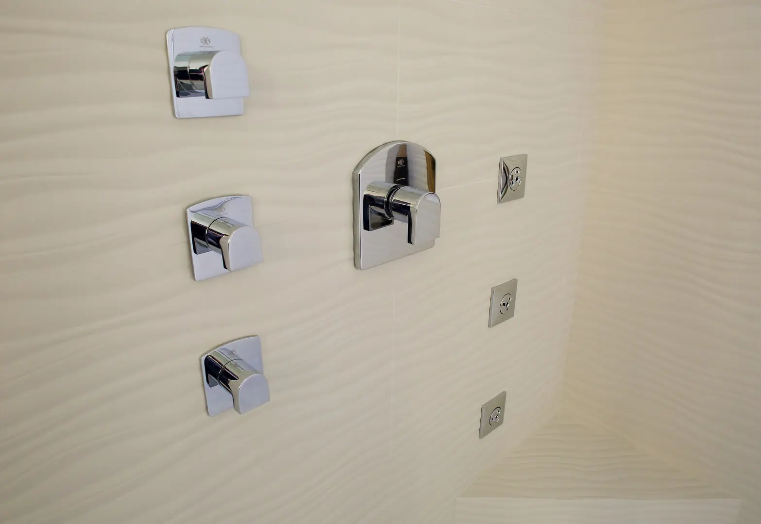 A bathroom wall with several different sized tiles.