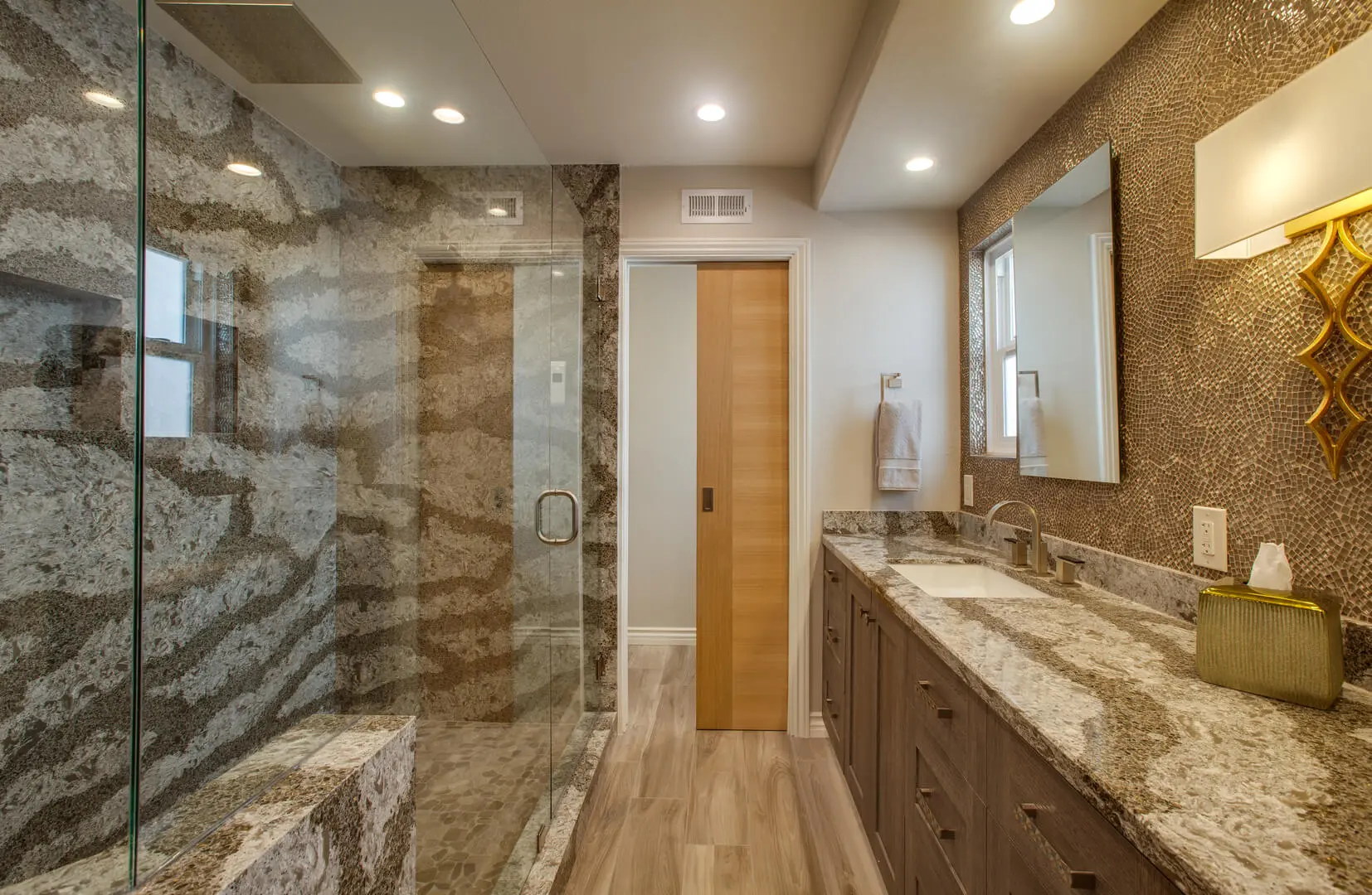 A bathroom with marble counter tops and wooden cabinets.