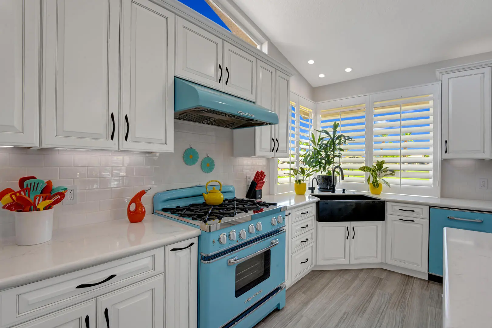 A kitchen with white cabinets and blue oven.