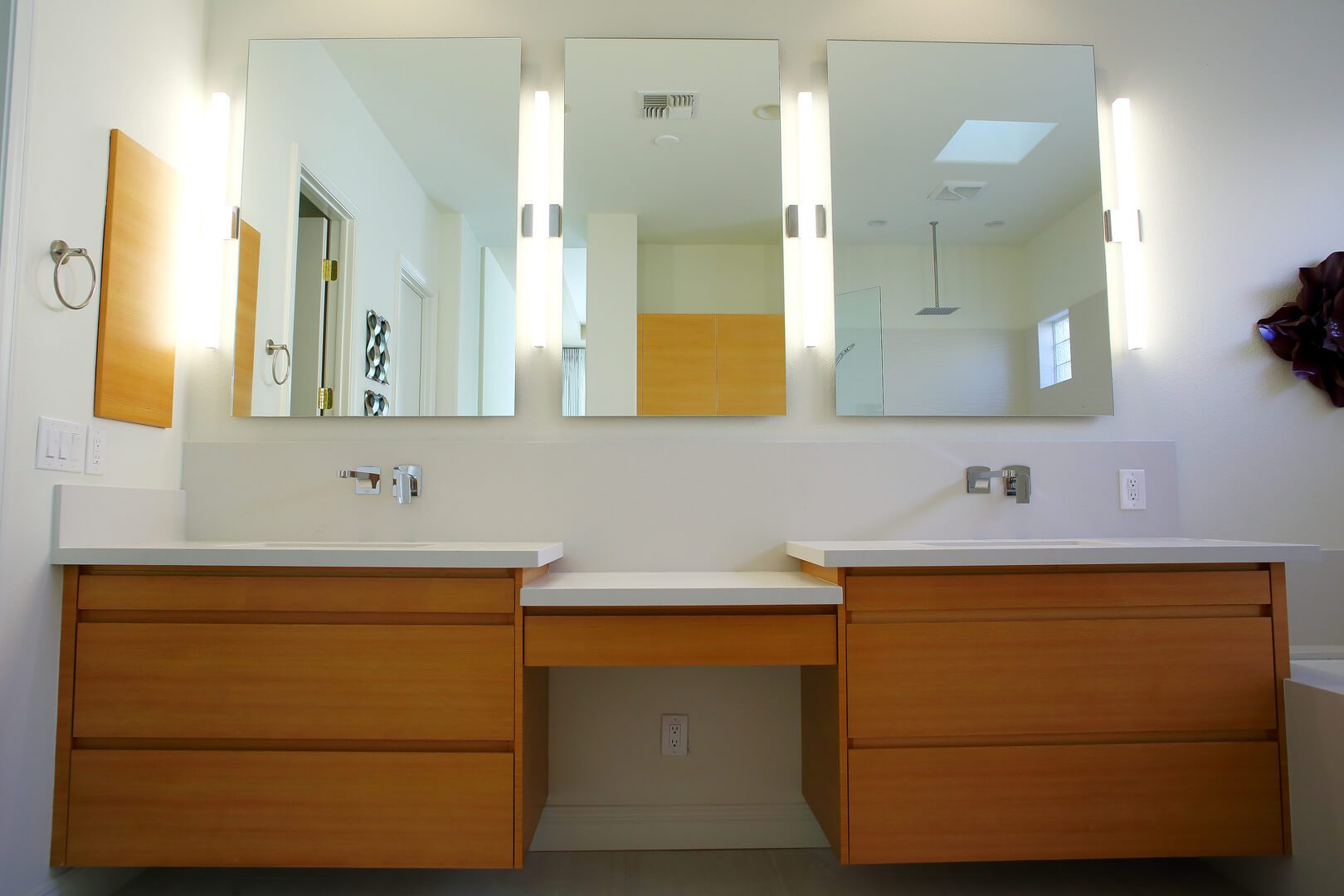 A bathroom with two sinks and three mirrors.