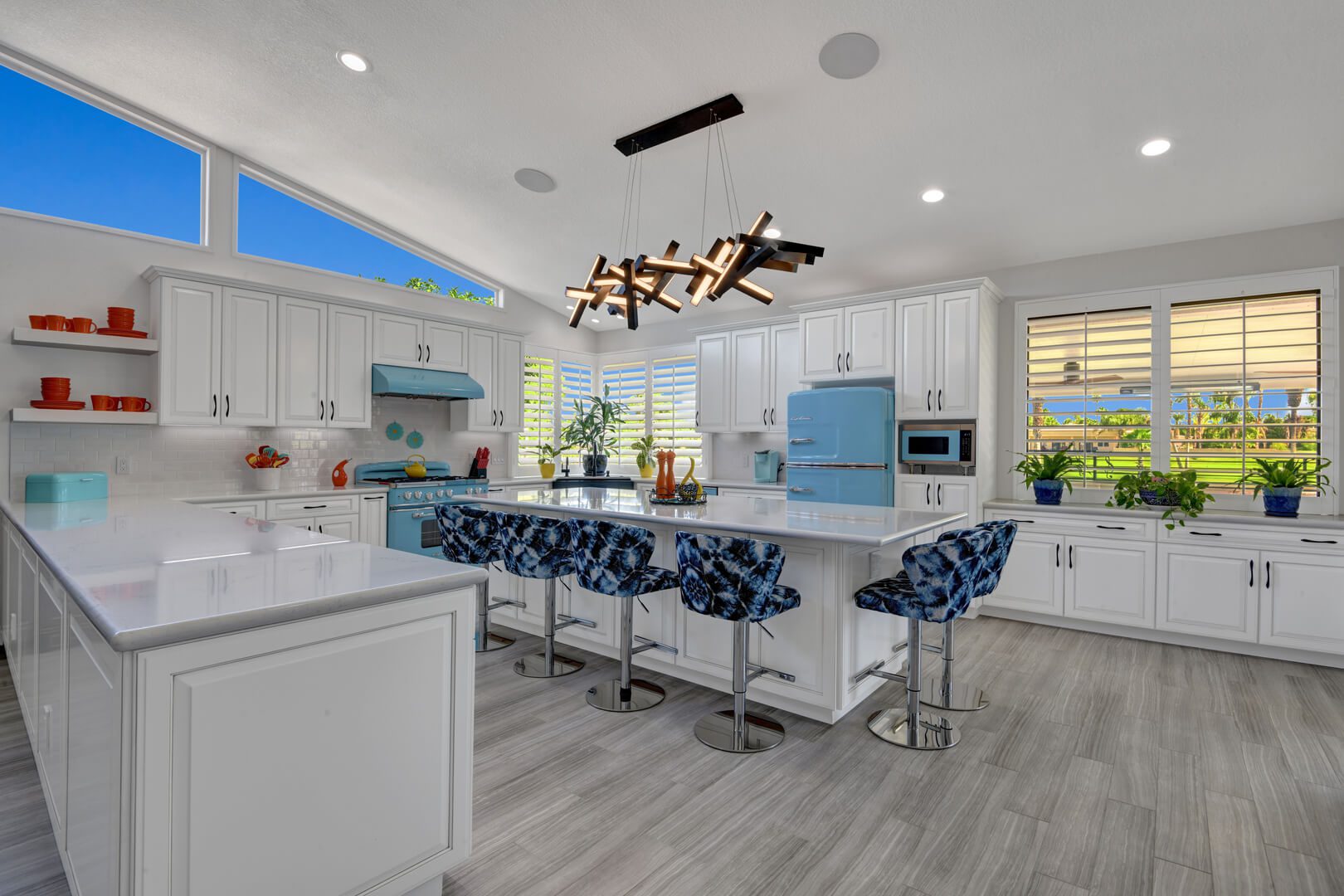 A kitchen with white cabinets and blue chairs.