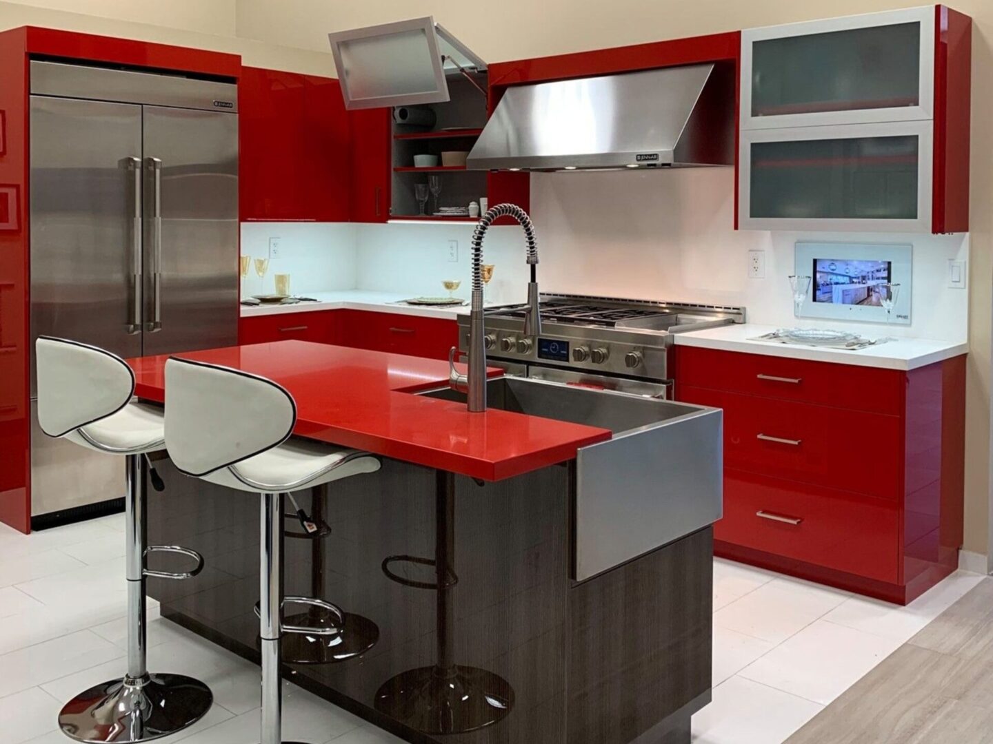 A kitchen with red and black cabinets, white counter tops.