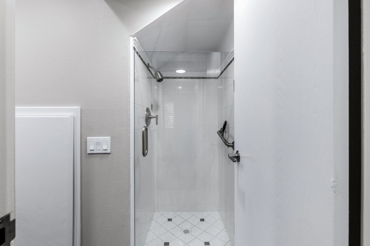 A white shower stall with tiled floor and walls.