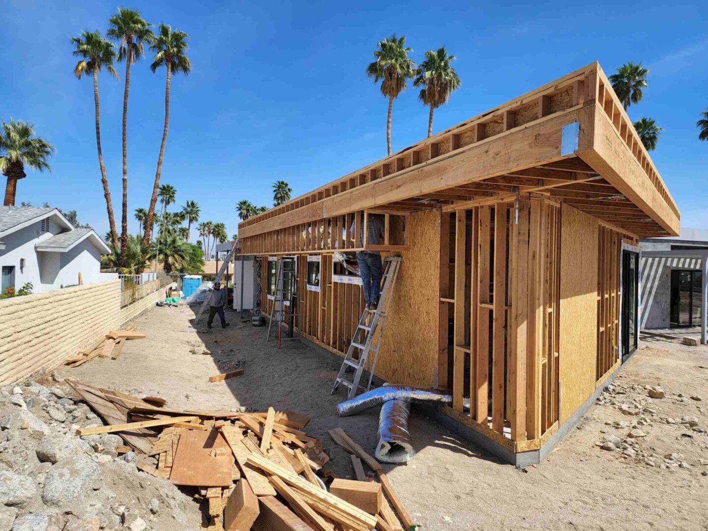 A house being built with palm trees in the background.