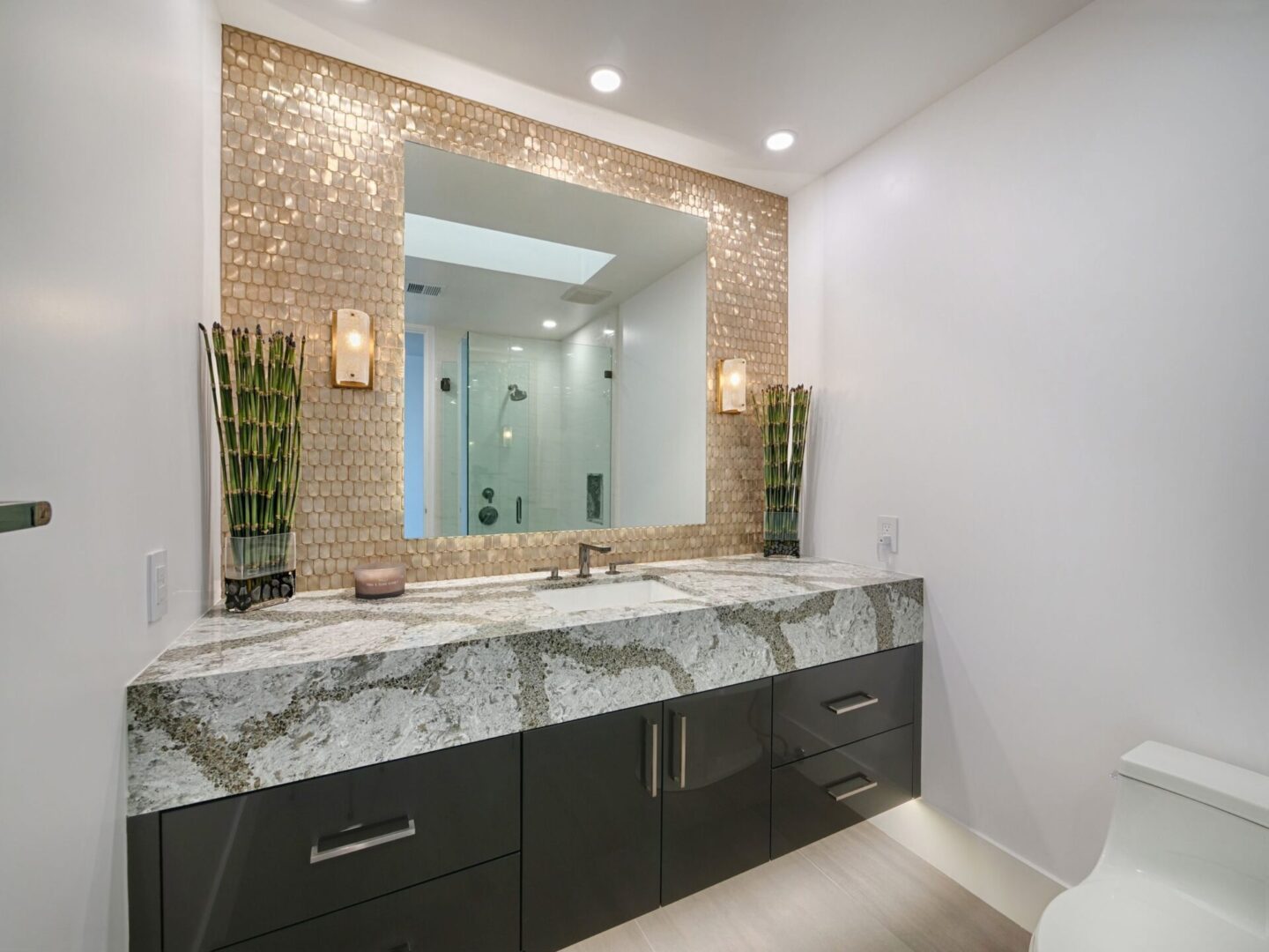 A bathroom with a large marble counter and a mirror.
